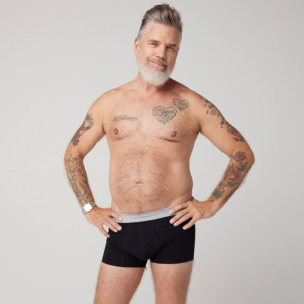 Mann trägt TENA schützende Inkontinenz-Boxershorts.