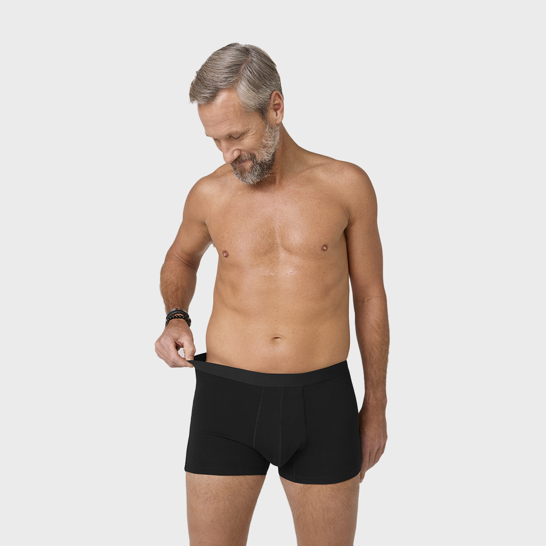 NEUE TENA Men Schützende Boxershorts, getragen von einem Mann ohne Hemd.