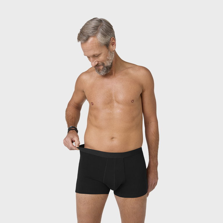 NEUE TENA Men Schützende Boxershorts, getragen von einem Mann ohne Hemd.