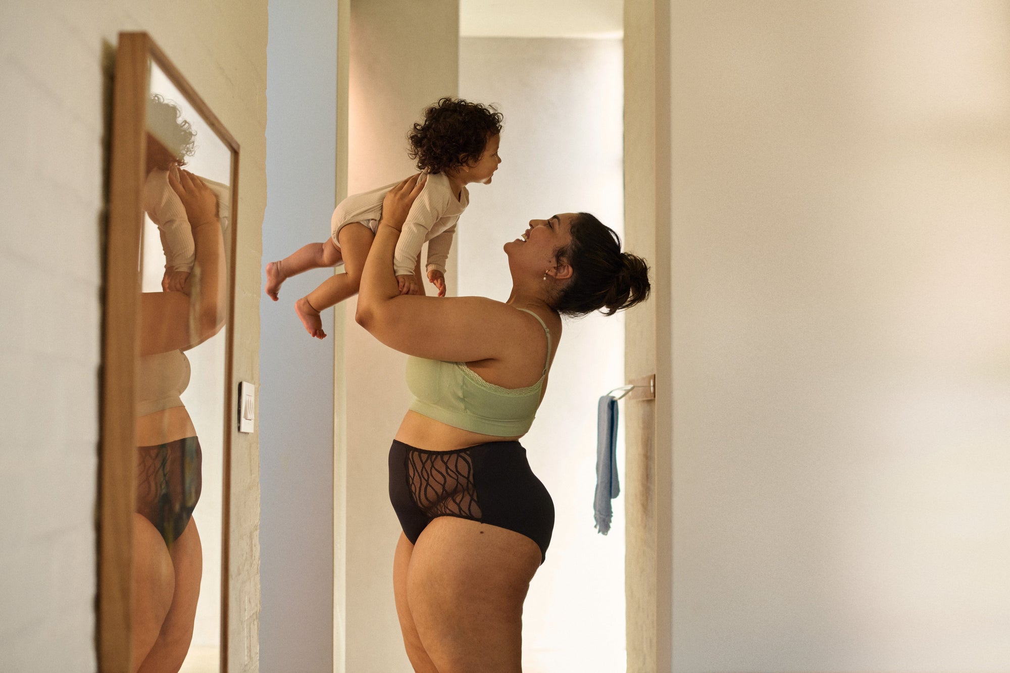 Mutter spielt mit Baby in gemütlicher Umgebung mit schützender Unterwäsche