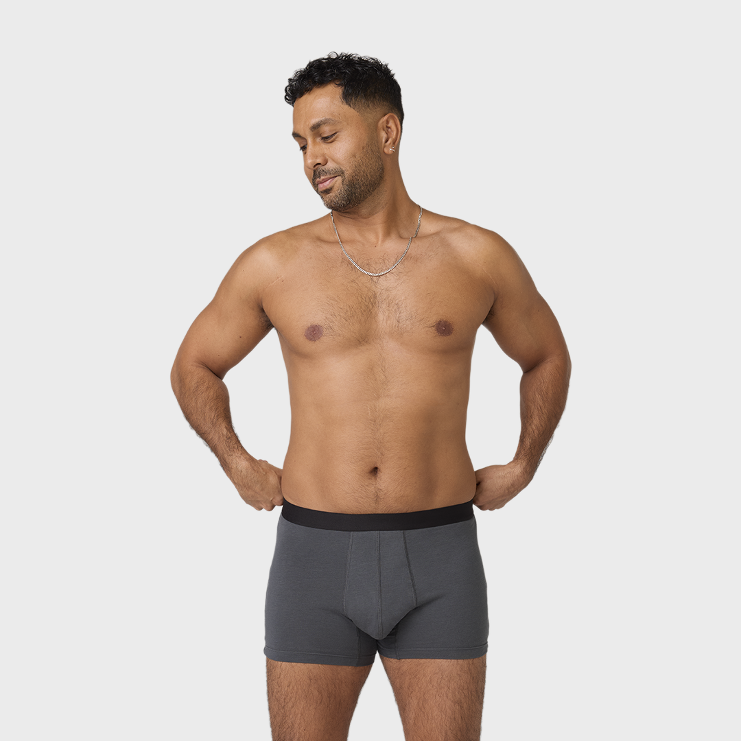 NEUE TENA Men schützende Boxershorts, getragen von einem Mann, der sie anpasst.